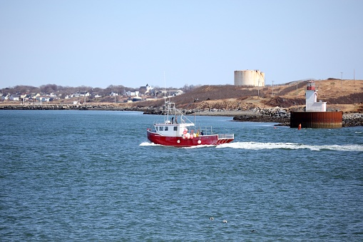 Lighthouse and fishing boat in the harbor of Yarmouth Nova Scotia. The lighthouse is Bunker lighthouse. Selective focus on lighthouse.