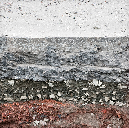 A cross section through a tarmac road surface, showing levels of rock and earth below.