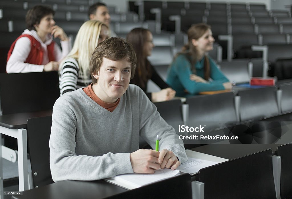 Retrato de estudante do sexo masculino com amigos em sala de aula de universidade - Foto de stock de Estudante royalty-free