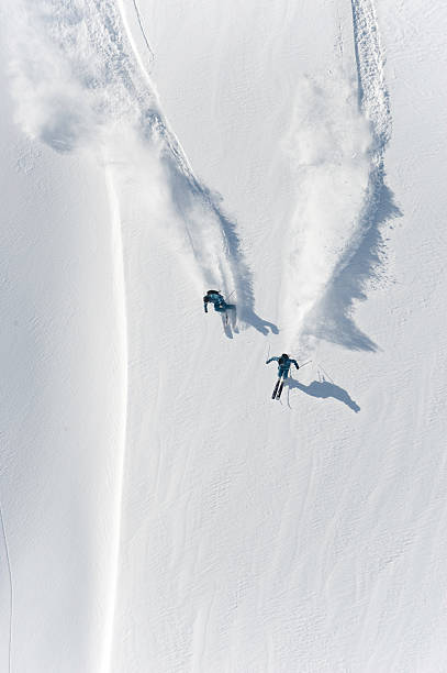 aerial view of two skiers skiing downhill in powder snow - heliskiing bildbanksfoton och bilder