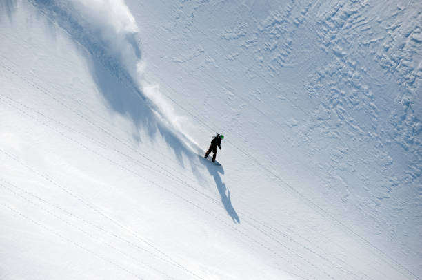 istock Snowboarder speeding down hill in powder snow flowing behind 157590190