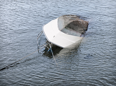 An overturned boat sinking in deep water.