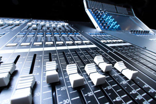 Dramatically lit detail of a new digital sound board, referred also to a console or desk.  This piece of high tech equipment is used in professional applications for live sound reinforcement and recording of music and spoken word.