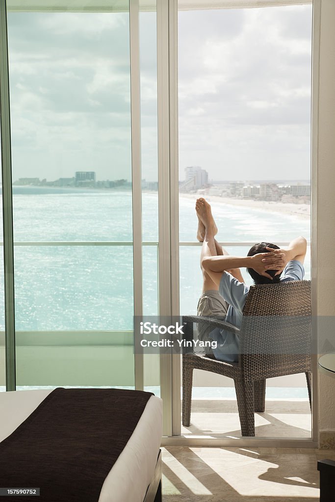 L'homme se détendre sur le balcon tout en profitant de la vue sur la plage - Photo de Plage libre de droits