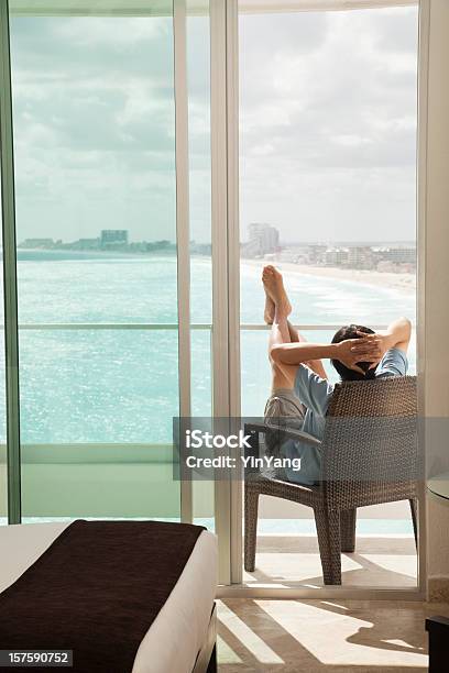 Photo libre de droit de Lhomme Se Détendre Sur Le Balcon Tout En Profitant De La Vue Sur La Plage banque d'images et plus d'images libres de droit de Plage