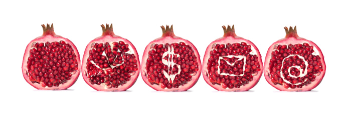 Stock photo showing a close-up, elevated view of healthy eating image of a layer of pomegranates (Punica granatum) seeds displaying red flesh (arils) encasing seeds on a red background.