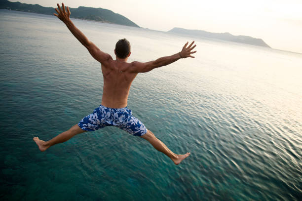 istock Man Makes Spreadeagle Jump into Green Sea 157591294