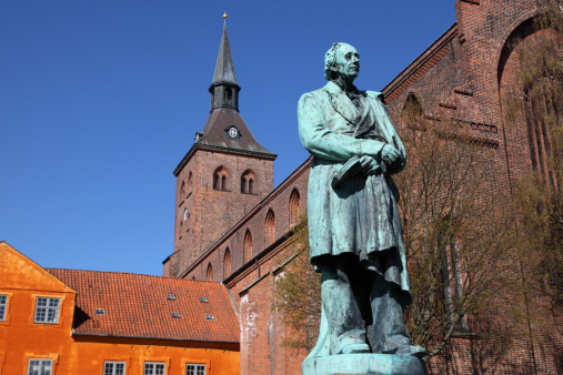 Sculpture of World Famous Danish fairy tale writer and poet Hans Christian Andersen (1805 - 1870) in front of the Sankt Knuds kirke (church) in Odense, the town where he was born.