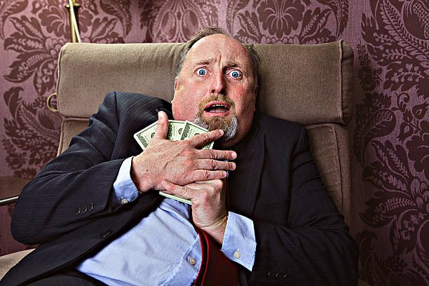 Afraid to loose money Middle aged man hugging US dollars with a frightrened facial expression greed stock pictures, royalty-free photos & images