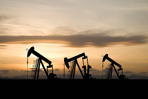 tres pumpjacks y un cielo amarillo - wellhead fotografías e imágenes de stock