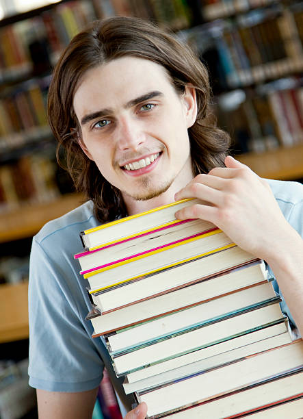istock Young Man with a Stack of Books at the Library 157591868