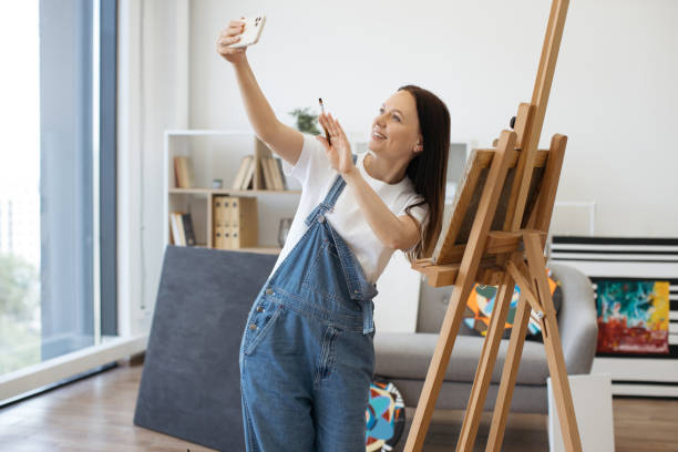 istock Smiling lady making selfie on smartphone in art studio 1575919081