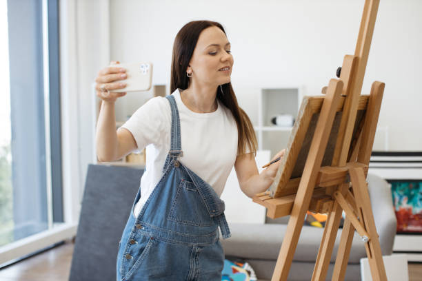istock Smiling lady making selfie on smartphone in art studio 1575919083