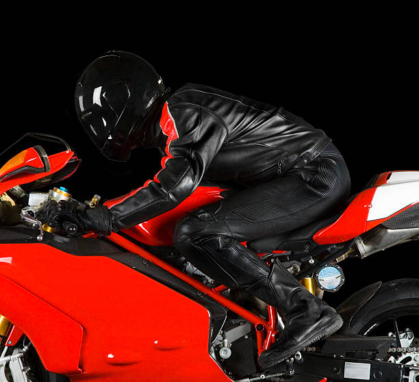 Biker in riding red superbike on black background stock photo