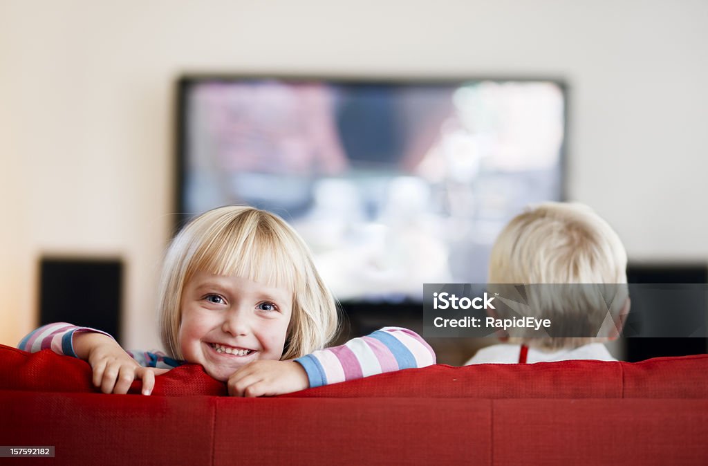 little girl sonrisas mientras little boy relojes televisión - Foto de stock de Televisión libre de derechos