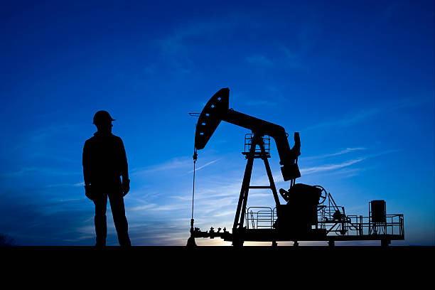 Blue Dusk Pumpjack and Oil Worker  oil pump petroleum equipment development stock pictures, royalty-free photos & images