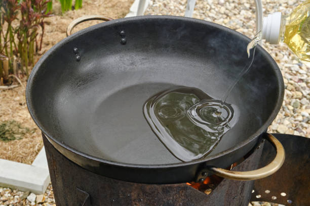 istock Cooking oil flowing in a cast iron pan. 1575925770