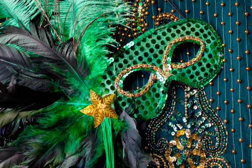 Mardi Gras mask with feathers and gold star on beaded background.