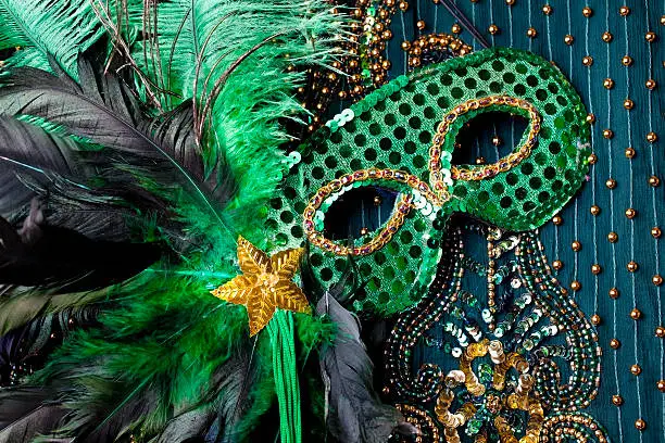 Mardi Gras mask with feathers and gold star on beaded background.