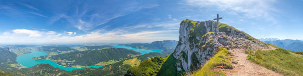 landscape with top of Mount Schafberg and mountains and Lake Mondsee and Attersee, Alps, Austria panoramic landscape with top of Mount Schafberg with cross and mountains and Lake Mondsee and Attersee, Alps, Austria attersee stock pictures, royalty-free photos & images