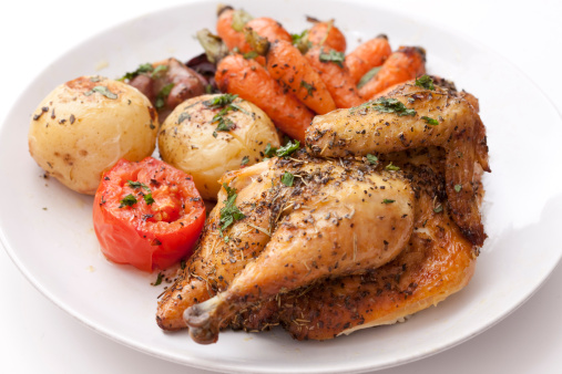 two juicy grilled chicken breasts on a white ceramic tray for serving with vegetables. front view. cement grey background. delicious food