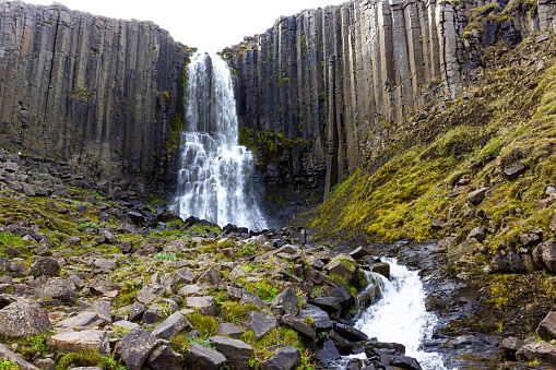 Waterfall and basalt columns in Iceland. Famous landmark. Road trip travel destination.