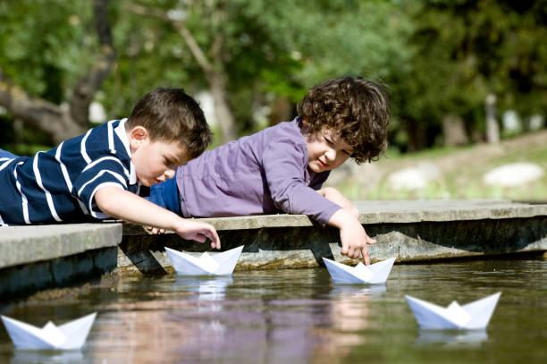 Two boys playing paper boat