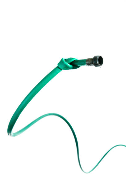 Water hose in a knot. A photograph of a water hose knotted with a droplet of water. Concept for water use, drought and conservation. water hose stock pictures, royalty-free photos & images