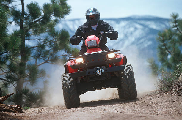 ATV traveling down a dust mountain trail.