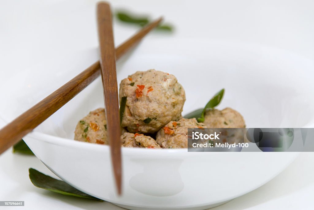 Asian Meatballs A white bowl with Asian meatballs and kafir lime leaves, with chopsticks. Asian and Indian Ethnicities Stock Photo