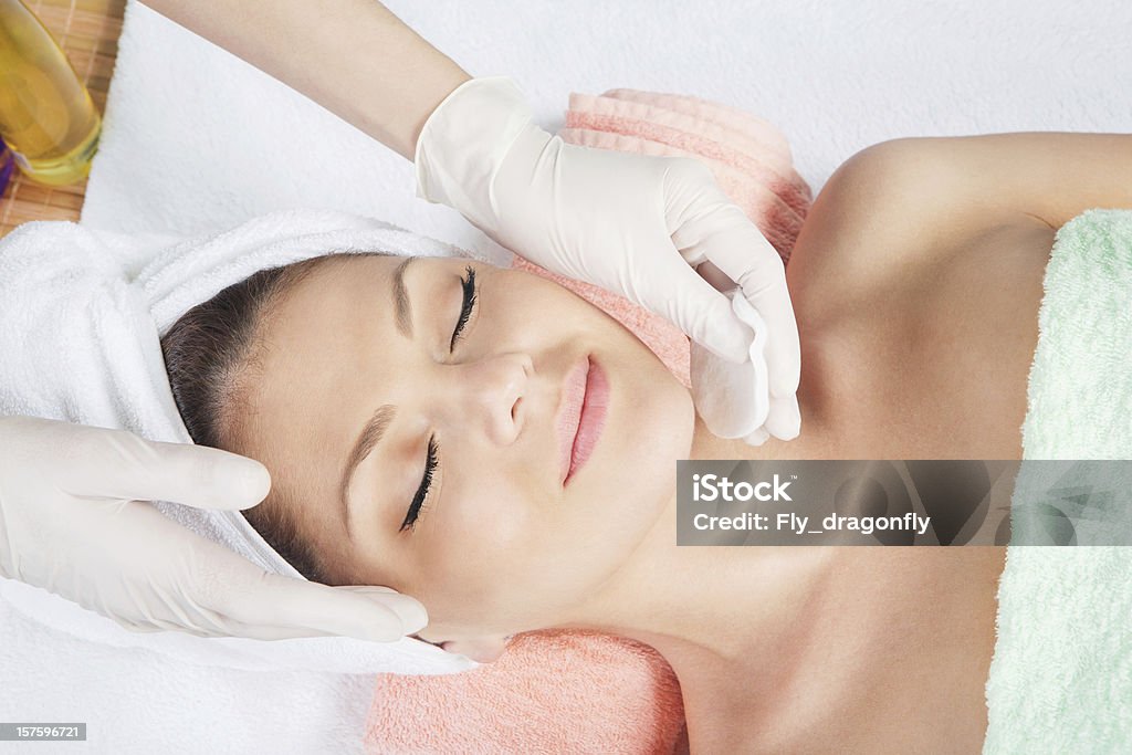 cosmetic treatment at spa salon Cosmetologist medical gloves is touching girl's face.  Facial Mask - Beauty Product Stock Photo