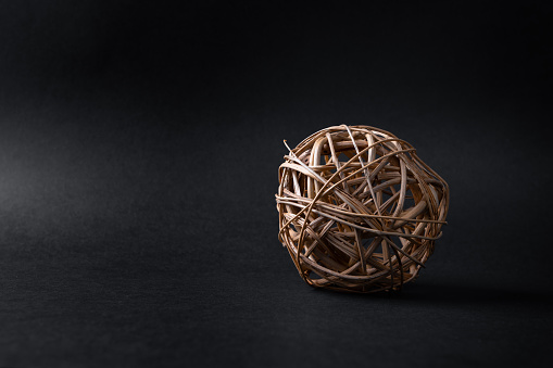 Wooden ball on dark background. Woven wicker or bamboo ball used for decorating
