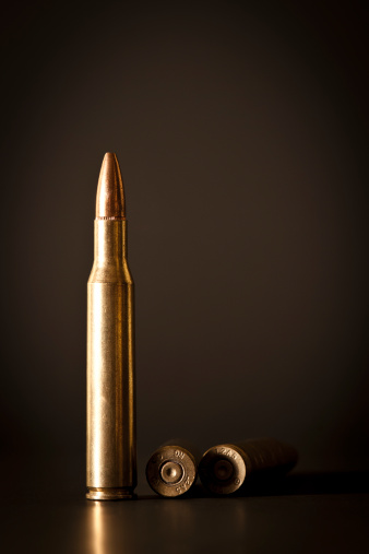 A standing-tall 7.62 mm caliber bullet with other two shells, isolated on black background, with copy space.