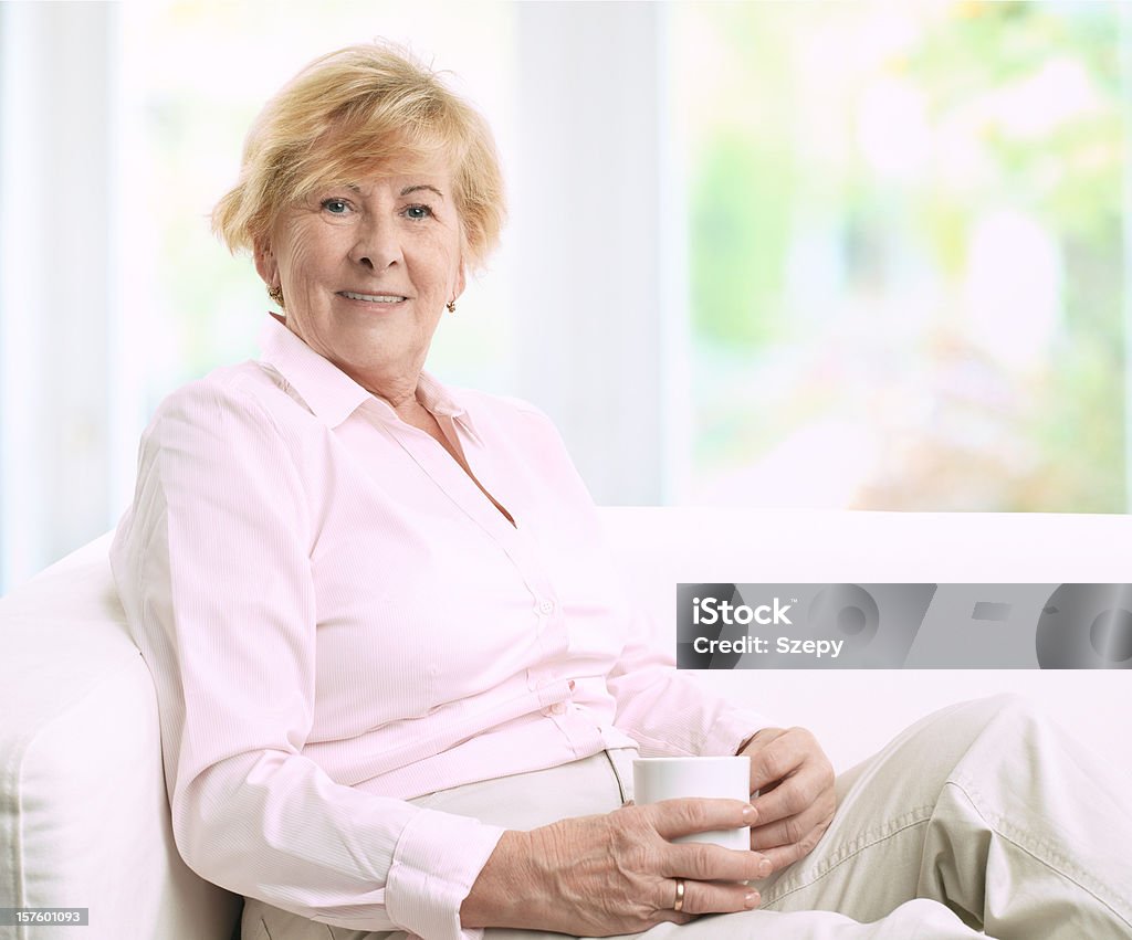 Senior Woman Happy senior woman sitting on a couch while she is drinking a cup of coffee 50-59 Years Stock Photo