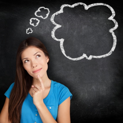 Woman thinking blackboard concept. Pensive girl looking at thought bubble on chalkboard / blackboard texture background. Mixed race Asian Chinese / Caucasian student.