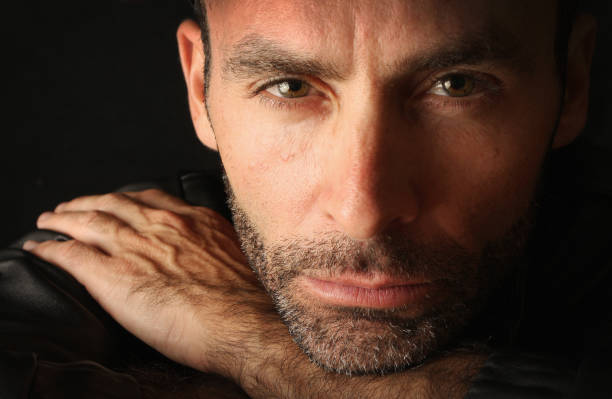 Close-up studio portrait of a handsome man in a black leather jacket . Against a black background