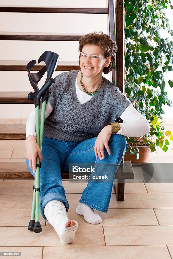 Heureuse femme avec une jambe cassée et béquilles - Photo de Jambe cassée libre de droits