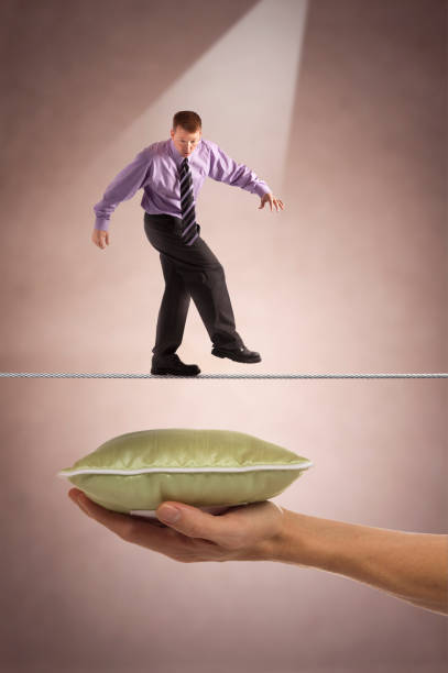 Businessman on tightrope with safety below stock photo