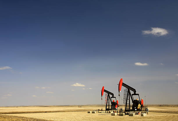 Two pumpjacks on the prairie. Bakken Oil Field, North Dakota, United States. Oil industry. Additional themes include crude oil, pipeline, storage, tanks, oil rig, industry, industrial equipment, prairie, geology, engineering, natural gas, keystone pipeline, gas, methane, fossil fuel, and production.  
