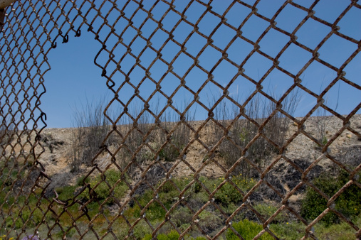 Fence in desert with hole. Concept for illegal immigration. High resolution found on istockphoto.com.