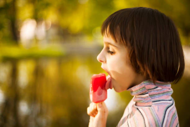 Mother is giving ice cream to her baby girl on the beach