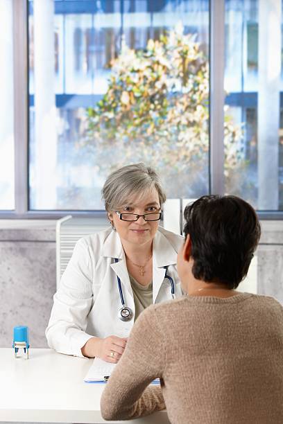 Older female doctor talking to patient in office stock photo