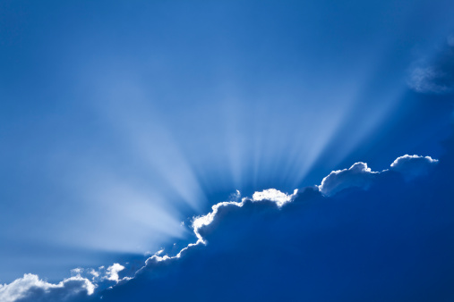 Sunrays burst above cloud, with dramatic rim lighting.