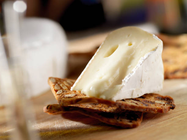 brie käse mit kräckern mit wein - cheese focus on foreground on top of portion stock-fotos und bilder