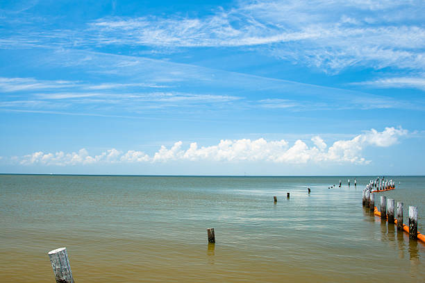 Wooden pier with posts and ropes with sparkling sea water. Wooden pier with blue sea background.