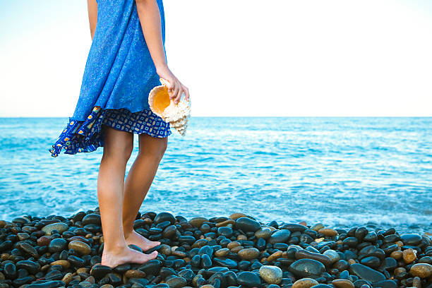 Young girl holding a sea conch at the beach.