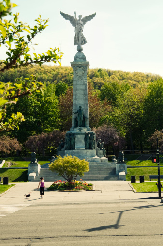 Woman waiting to cross Park Avenue with her dog in front of one of the most impressive monument of Montreal, the \