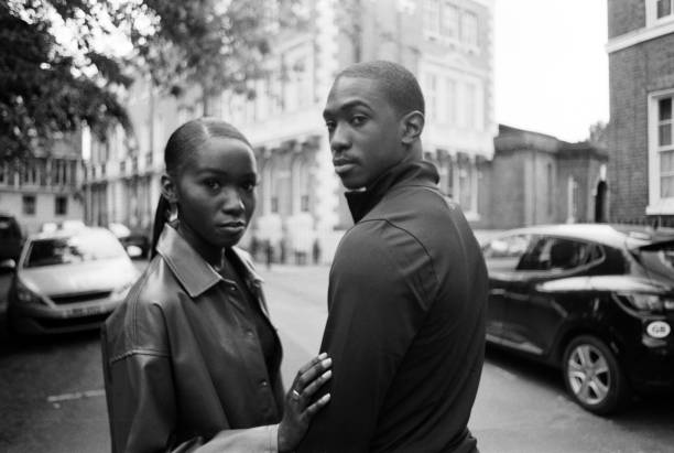 Analog film portrait of twins looking at camera. They are in a street and the image is in monochrome.