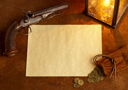 Antique Flintlock Pistol with Gold coins and blank paper - plenty of Copy Space. Lit by candlight from an old lantern, this has very moody feel to it - great Pirate Theme or as a Wanted Poster. Horizontal Image.