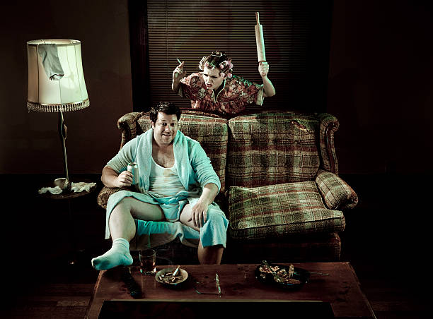istock Slob Man watching television while smoking woman waves rolling pin 157604011